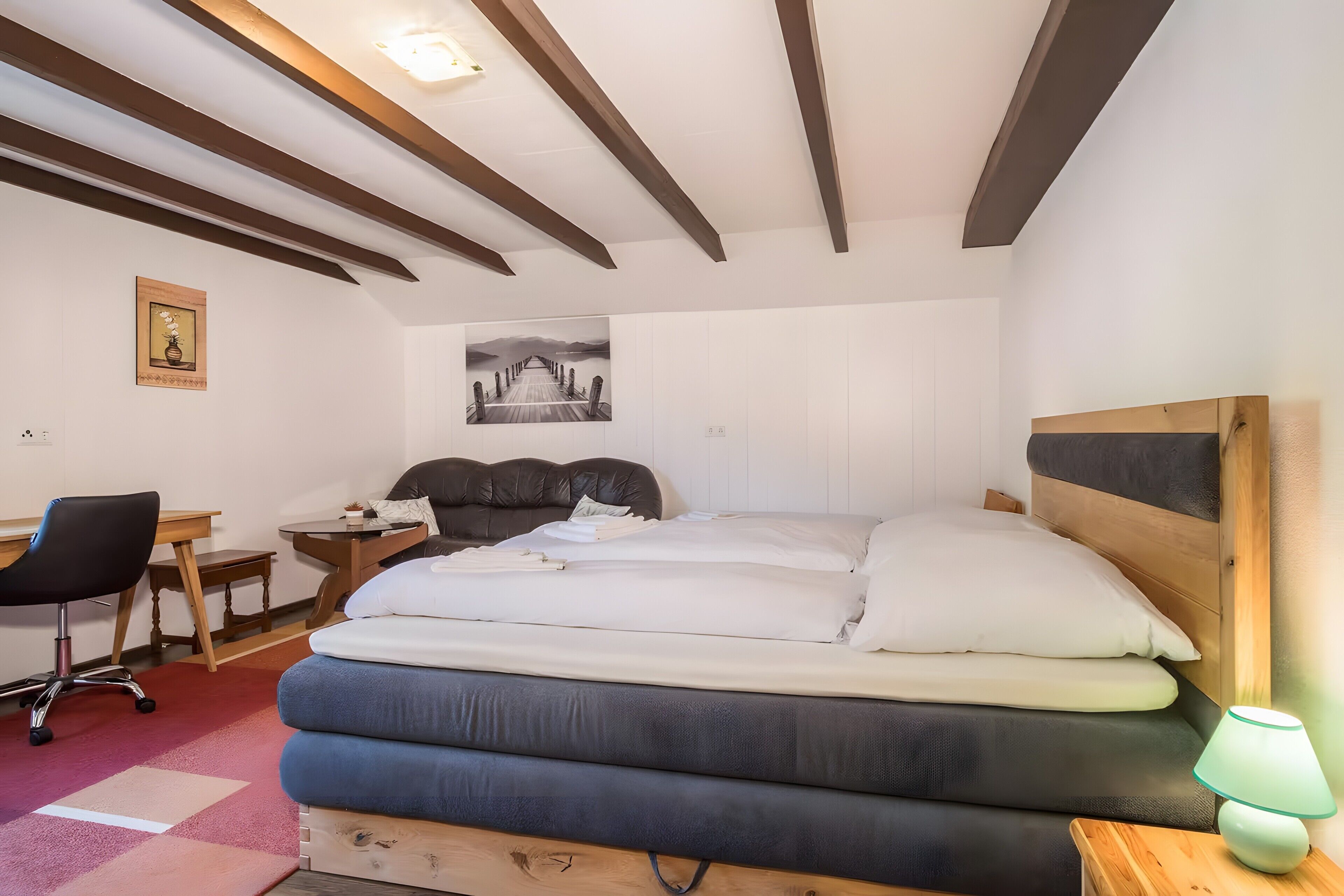 A bedroom with a bed, desk, chair, and a lamp.