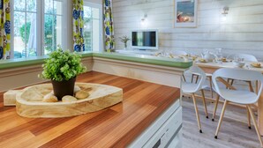 Una cocina moderna con encimera de madera, sillas blancas y una mesa de comedor.