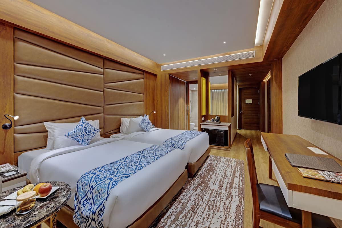 Ein Hotelzimmer mit zwei Betten, einem Schreibtisch und einem Fernseher.
