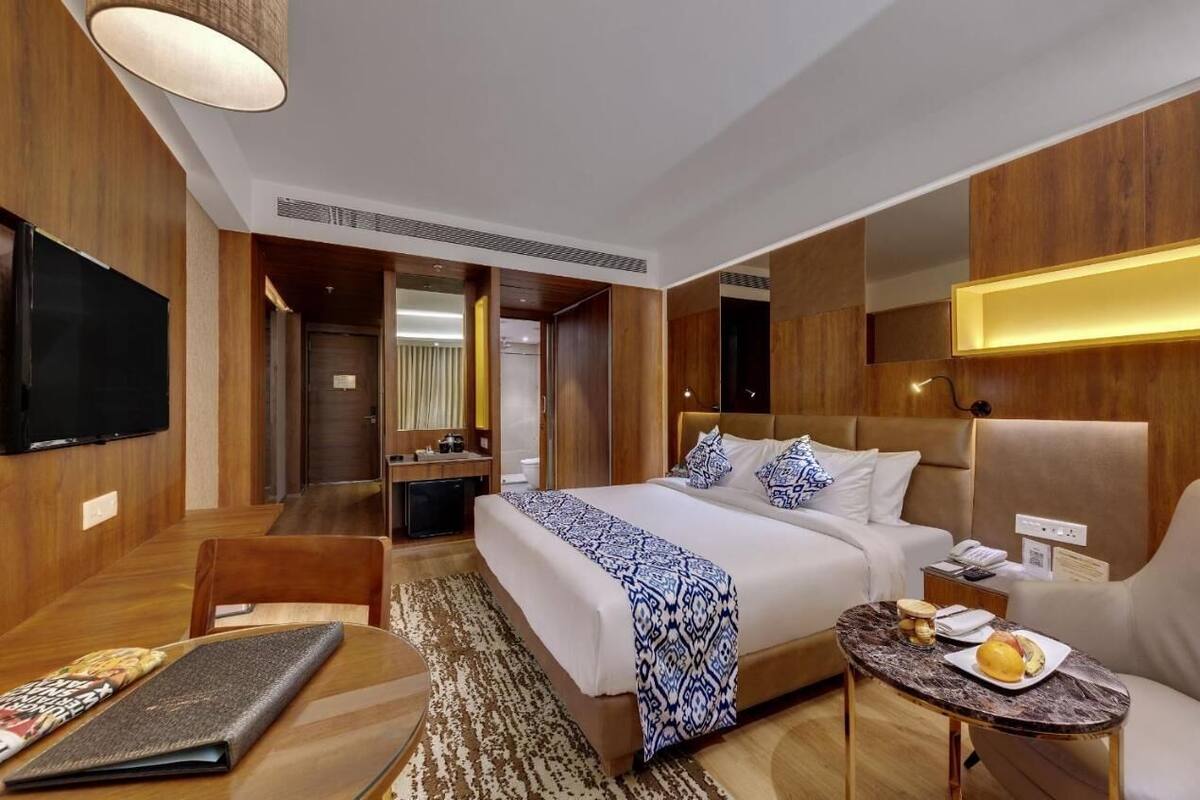 Ein Hotelzimmer mit einem großen Bett, einem Schreibtisch, einem Stuhl, einem Fernseher und einem kleinen Tisch mit einer Schüssel Essen.