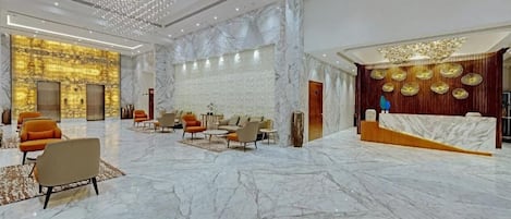 A spacious lobby with marble flooring, seating areas, and a reception desk.