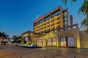 A hotel with a modern design, featuring a prominent sign for 'The Fen Resort & Club' and a well-lit entrance with a covered area. - The Fern Leo Resort & Club Junagadh (Junagadh)