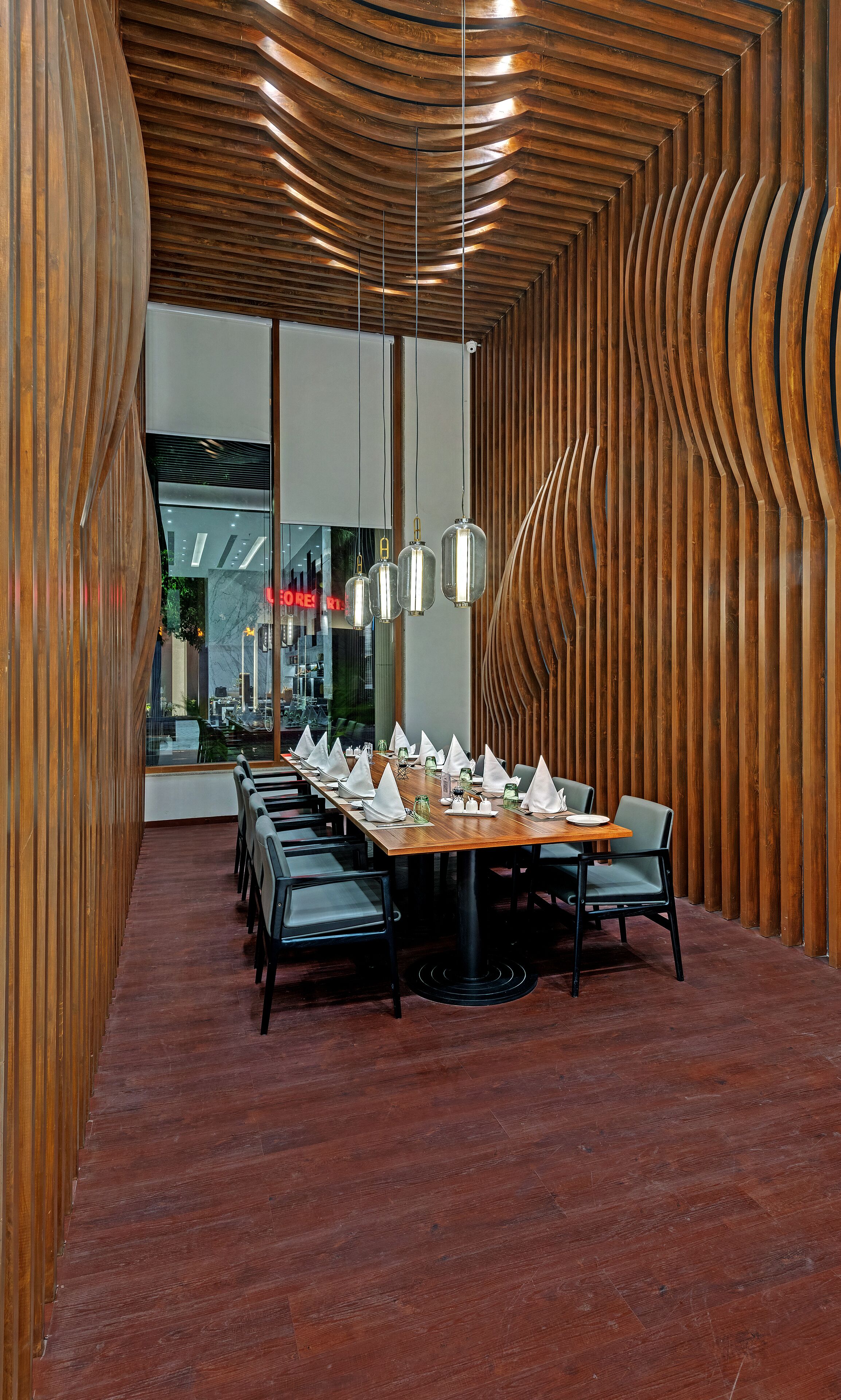 Un comedor moderno con una larga mesa de madera dispuesta para una comida, rodeada de sillas.