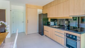 Een moderne keuken met houten kastjes, roestvrijstalen apparatuur en een glazen spatwand.