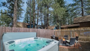 Patio trasero con jacuzzi, mobiliario exterior y valla de madera.