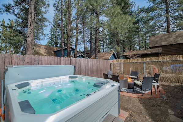 Un jardin avec un jacuzzi, un espace salon extérieur et une clôture en bois.