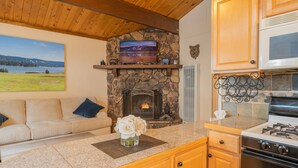 Un salón acogedor con chimenea de piedra, televisor de pantalla plana y sofá.