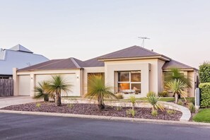 A single-story house with a garage, a front porch, and a small garden with palm trees. - Back 9—Family-friendly Golf Lover’s Retreat (Dunsborough)