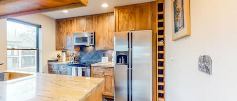 Enjoy cooking in this well-lit kitchen with a refrigerator, microwave, and granite countertop.