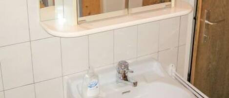 A bathroom with a white sink, wooden cabinet, and a mirror above the sink.