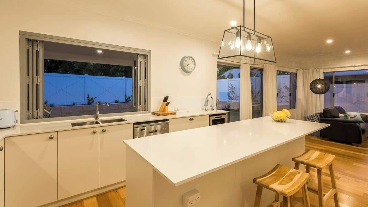 A modern kitchen with a large island, a dining area with a sofa, and a view of the outside.
