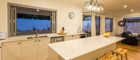 Una cocina moderna con una isla grande, un comedor con sofá y vistas al exterior.