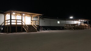 Um amplo edifício industrial com área externa coberta, incluindo uma escadaria que leva a um terraço.