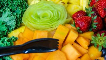 A variety of fresh fruits and vegetables including kale, pineapple, strawberries, and cantaloupe.