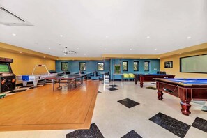 Une salle équipée de tables de billard, d’une table de ping-pong et d’un écran de projection.