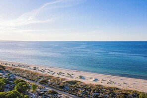 Un paysage côtier avec une plage, une route et une végétation clairsemée.