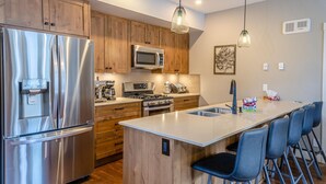 A modern kitchen with stainless steel appliances, wooden cabinets, and a central island with bar stools.