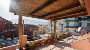 Enjoy breathtaking views of the urban landscape from this rooftop terrace with a pergola and lush greenery.