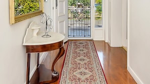 Un couloir avec une porte blanche, un miroir, un lavabo et un tapis à motifs.