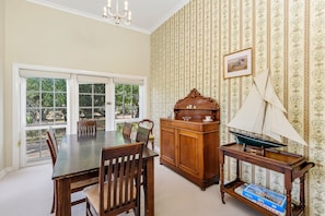 A dining area with a table and chairs, a wooden sideboard, a ship model, and a framed picture on the wall. - Normanville - Historic home newly updated (Normanville)