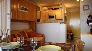 Eine kleine Küche mit Holzschränken, einer Mikrowelle und einem Kühlschrank.