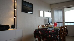 Ein Essbereich mit Tisch für zwei Personen, einem Fernseher und einem fenster mit Vorhängen.