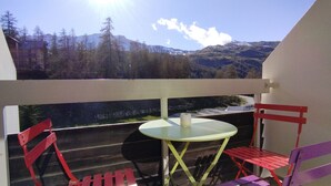 Ein Balkon mit Tisch und Stühlen, mit Blick auf eine gebirgige Landschaft.