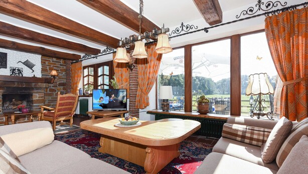 A cozy living room with a fireplace, wooden furniture, and large windows offering a view of the outdoors. - Vacation home Koppelblick in the house Hohe Lucht in Dunum - Holiday home Koppelblick in the house Hohe Lucht in Dunum (Dunum)