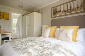 A bedroom with a large bed, a desk, and a wardrobe. - Hollicarrs - Woodland Lodge (York)