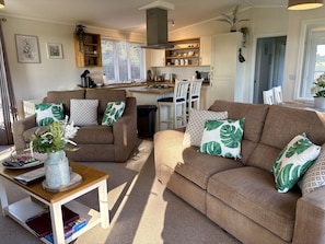 Ein gemütliches Wohnzimmer mit zwei Sofas, einem Couchtisch und einer Küche im Hintergrund.