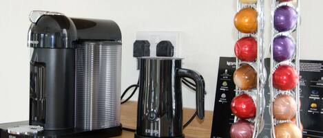 A coffee maker, a Krups coffee pot, and a coffee pod holder on a wooden surface.