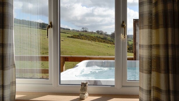 Habitación con un ventanal grande con vistas a un jacuzzi y un paisaje cubierto de césped.
