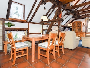 A rustic dining area with a wooden table and chairs, a radiator, and a cabinet in the background.