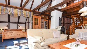 Een gezellige kamer met een houten plafond, een bank, een houten tafel en een open haard.