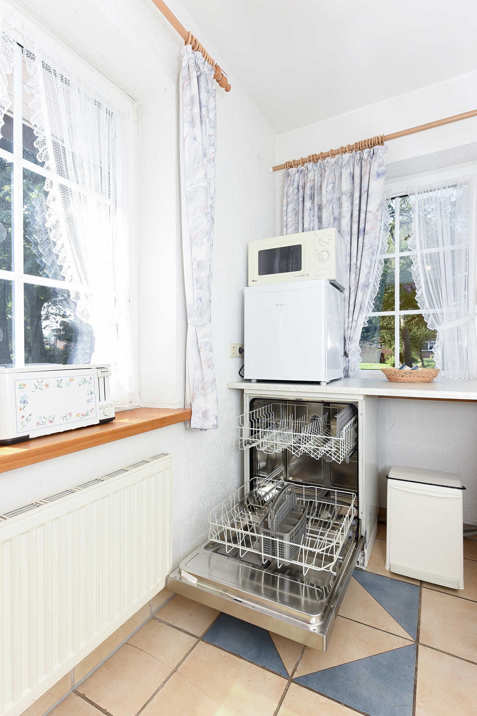 A kitchen with a built-in dishwasher, a microwave, and a small refrigerator.