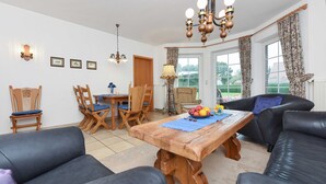 Een woonkamer met een houten tafel, twee banken, een eettafel met stoelen en een kroonluchter.