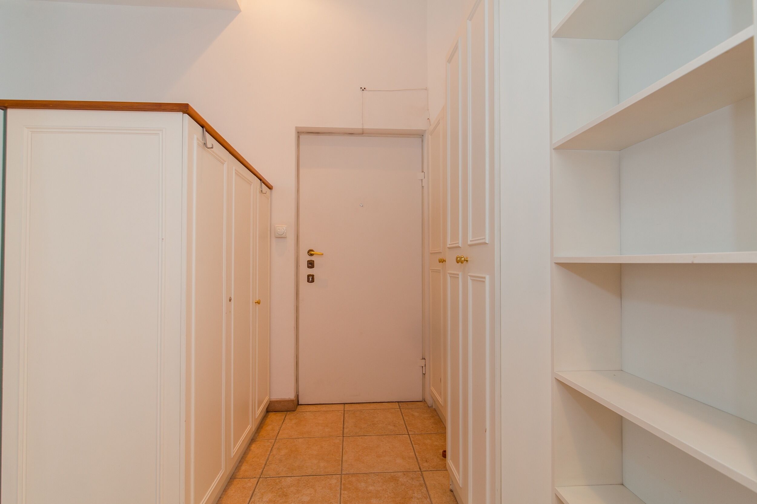 A narrow hallway with white doors and a tiled floor.