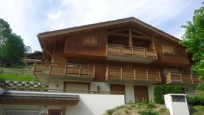 Eine zweistöckige Holzhütte mit Balkonen, einer Garage und einer Steinsichtmauer.