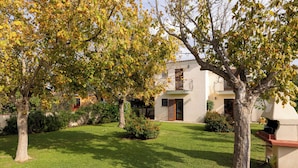 A well-maintained garden with a lawn, trees, and a building with a balcony. - Le Dimore di Budoni (Budoni)