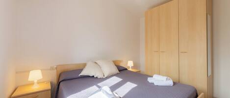 A neatly made bed with pillows, a bedside lamp, and a folded towel on the bed.