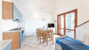 A compact kitchen with a dining area, a TV, and a window with a view. - Le Dimore di Budoni (Budoni)