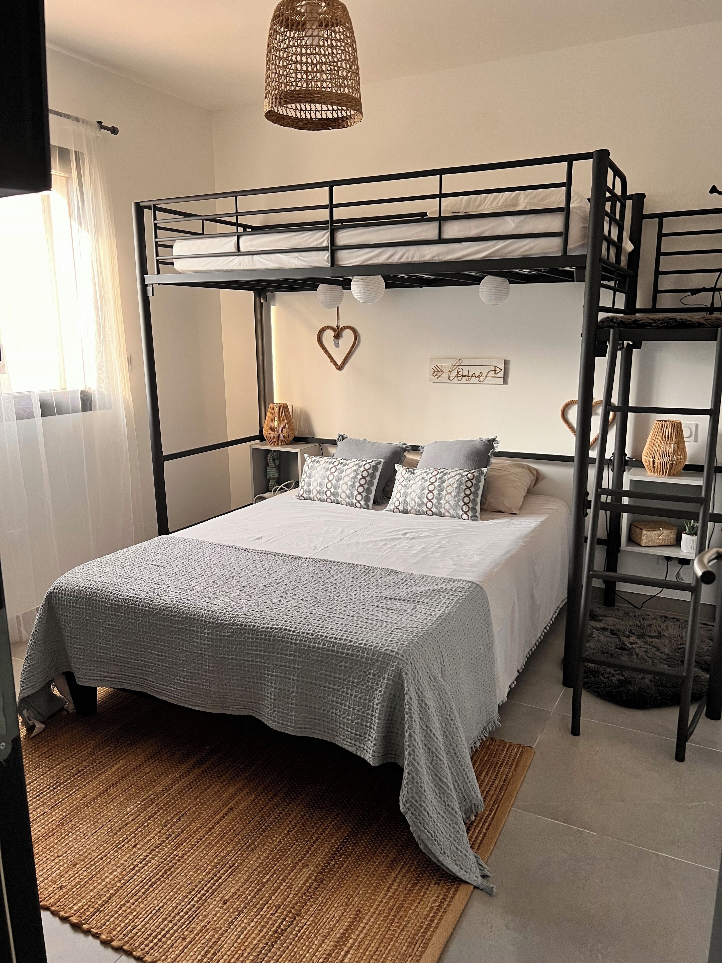 A bunk bed room with a woven headboard, a heart-shaped decoration, and a 'Love' sign on the wall.