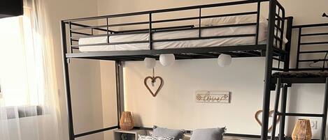 A bunk bed room with a woven headboard, a heart-shaped decoration, and a 'Love' sign on the wall.