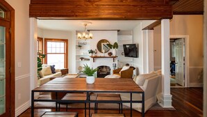 A dining area with a wooden table and benches, a fireplace, and a television mounted on the wall.