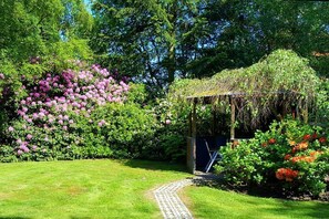 Ein Garten mit einem Pfad, der zu einem Gazebo führt.