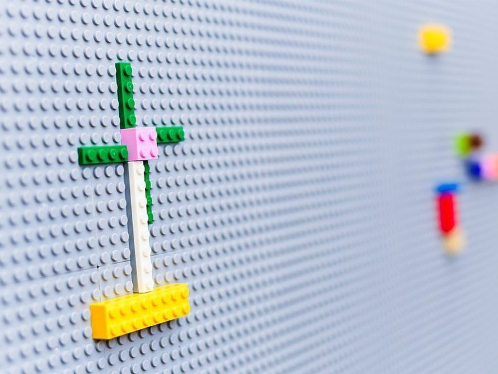 Una costruzione LEGO con una base verde, rosa e bianca, e un elemento inferiore giallo.