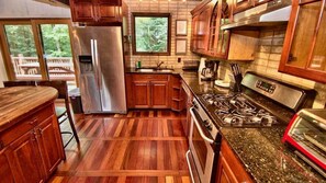Una cocina con armarios de madera, un refrigerador de acero inoxidable, una estufa a gas y una ventana con vista a una terraza.