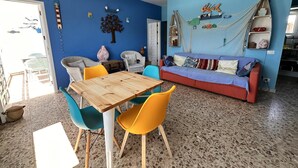 A room with a blue wall, a wooden table, colorful chairs, a red sofa, and a hammock. - Casa Azul Holiday Home (El Cotillo)