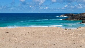 A beach with rocky terrain and a clear view of the ocean. - Casa Azul Holiday Home (El Cotillo)