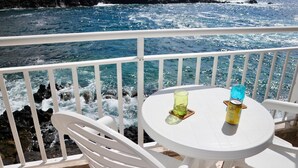 A balcony with white chairs and a table, overlooking a rocky coastline and the ocean. - Casa Azul Holiday Home (El Cotillo)